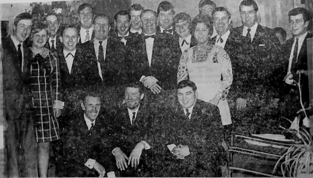 A large group of people in formal attire posing for a group photo indoors.