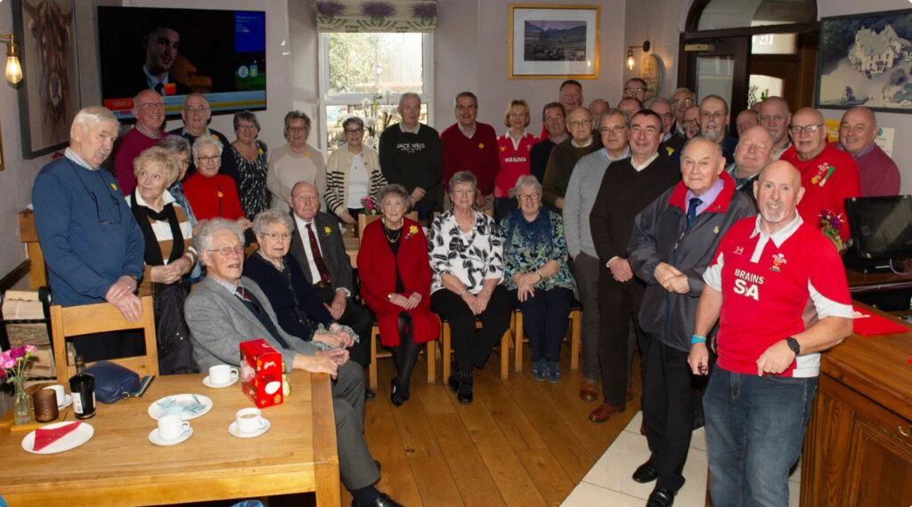 A large group of people posed for a group photo in a cozy living room.